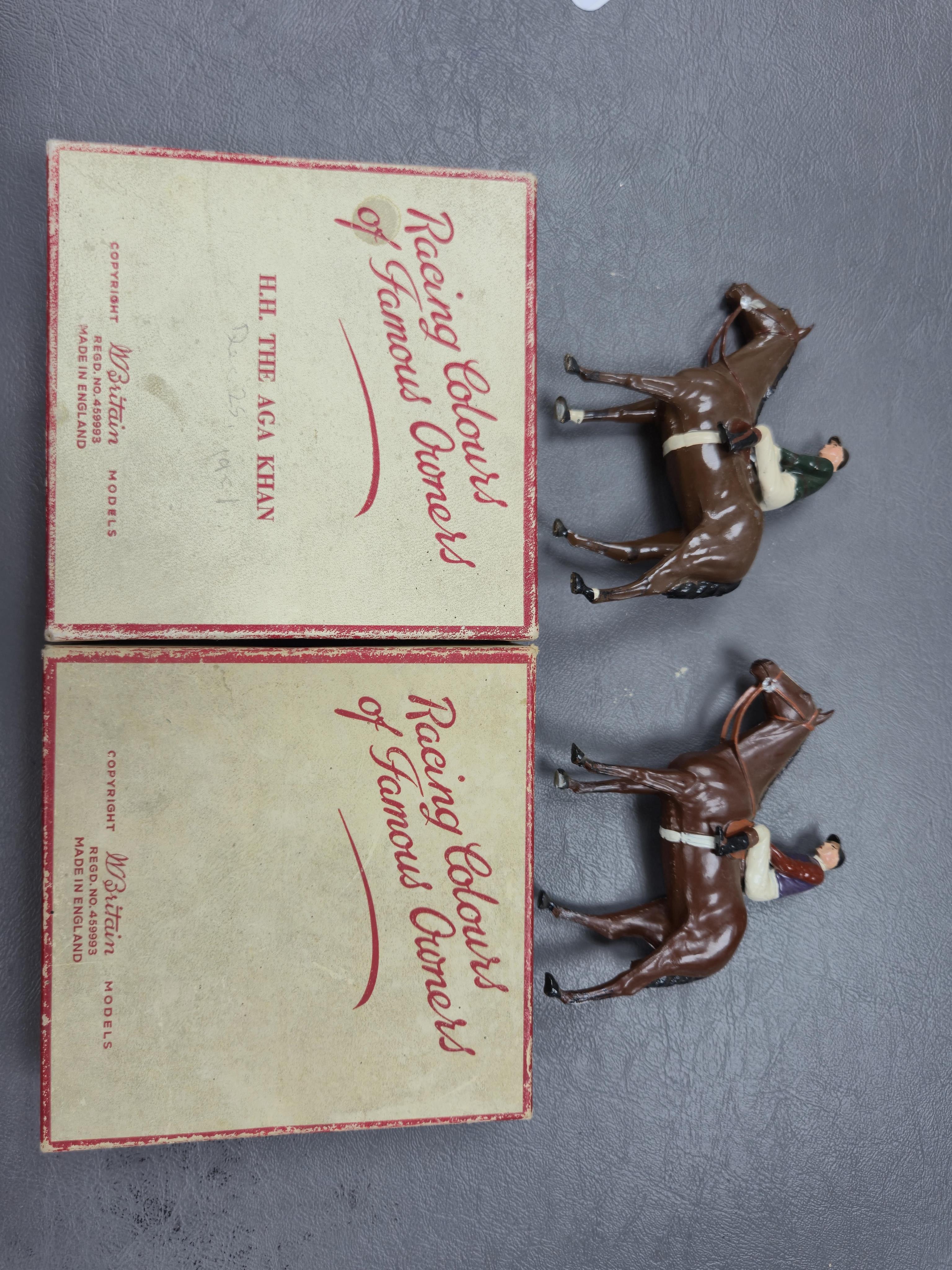 Two boxed Britains Racing Colours of Famous Owners series lead mounted figures; H.M. The Queen - rider in purple and brown jersey with gold frogging on a brown horse, and H.H. The Aga Khan - rider in dark green jersey on
